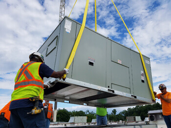 Crane lowering HVAC equipment onto rooftop